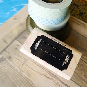 May include: A wooden stamp with a black rectangular area for stamping. The stamp has a decorative border with white flowers. The text "2007 STAMPIN' UP!" is printed on the side of the stamp.