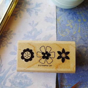 May include: A wooden stamp with three black and white flower designs. The stamp reads "Stampin' Up!" at the bottom.
