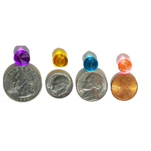 May include: Four small, round, faceted glass gems in different colors: purple, yellow, blue, and pink. The gems are placed on top of US coins to show their size.