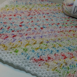Puede incluir: Una manta de bebé de crochet blanco con un hilo colorido multicolor. El hilo es un patrón moteado de rojo, azul, verde, amarillo y morado. La manta tiene un borde de crochet blanco.
