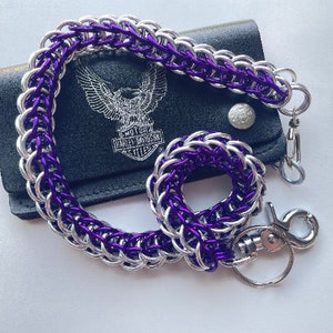 May include: A purple and silver chain wallet accessory with a matching key ring. The chain is draped over a black leather wallet with a Harley Davidson logo. The chain is made of interlocking metal rings.