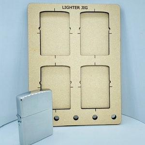 May include: A silver metal lighter next to a wooden jig with four rectangular cutouts. The jig has the words "Lighter Jig" printed at the top. The jig has three small holes at the bottom.