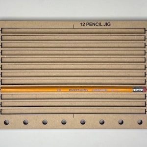 May include: A wooden jig with 12 slots for holding pencils, labeled "12 Pencil Jig". A yellow pencil is placed in one of the slots.