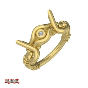May include: A gold ring with a diamond in the center, shaped like an eye. The ring is intricately designed with a twisted band.