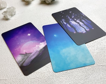 May include: Three tarot cards with different night sky scenes. The first card has a purple and blue sky with a crescent moon and a single star. The second card has a dark blue sky with a full moon and a single star. The third card has a dark blue sky with a forest silhouette.