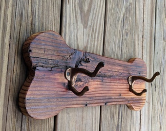 Può includere: Un attaccapanni in legno a forma di osso di cane con due ganci in bronzo antico. Il legno ha una finitura naturale e invecchiata con venature e nodi visibili. Per i proprietari di animali.