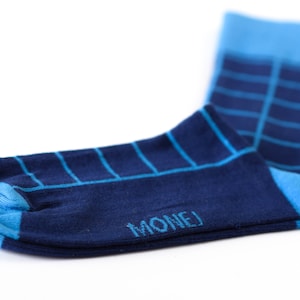 May include: A pair of blue and navy blue socks with a checkered pattern. The socks have the word "MONEJ" written on the bottom.