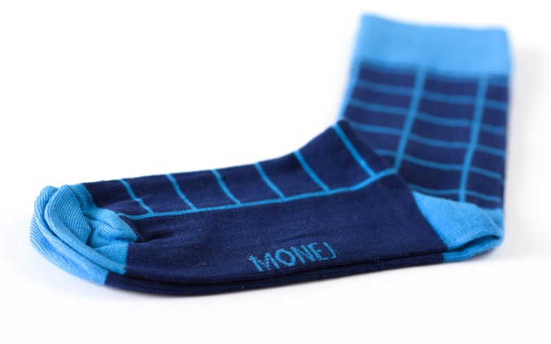 May include: A pair of blue and navy blue socks with a checkered pattern. The socks have the word "MONEJ" written on the bottom.