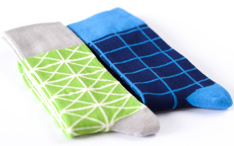 May include: Two pairs of socks with geometric patterns. One pair is green with a white geometric pattern and the other pair is blue with a white grid pattern.