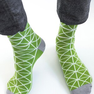 May include: A pair of green socks with a white geometric pattern. The socks have a gray toe and heel.