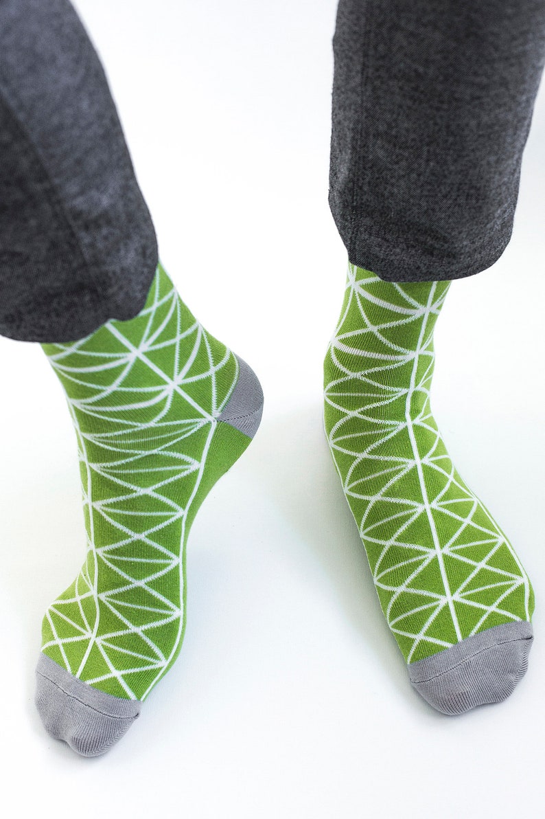May include: A pair of green socks with a white geometric pattern. The socks have a gray toe and heel.