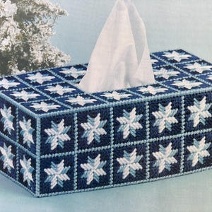 Op de afbeelding: Een blauwe en witte tissueboxhoes met een sneeuwvlokkenpatroon. De hoes is gemaakt van stof en heeft een witte tissuebox erin.