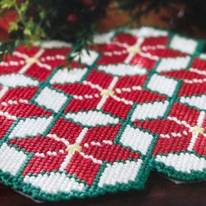 May include: Set of four red, white, and green crocheted placemats with a geometric pattern. The placemats are made with a repeating pattern of squares and diamonds.