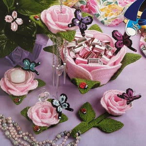 Peut inclure: Ensemble d'objets faits à la main en forme de rose rose, dont un bonbonnière remplie de Hershey's Kisses, des bougeoirs et des éléments décoratifs. Chaque pièce est ornée de feuilles vertes, de coccinelles et de papillons. Un collier avec des pendentifs en cristal transparent est également présent.