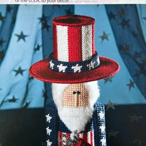 May include: A red, white, and blue Uncle Sam figure with a white beard and a top hat. The figure is holding a bundle of fireworks in its right hand. The figure is standing in front of a blue and white background with stars.