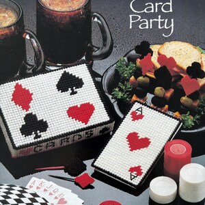May include: A craft project for a card game themed party. The image shows two white canvas boxes with black outlines and red and black card suit designs. One box says "CARDS" on the front. The other box has a single ace of hearts design. There are also playing cards, poker chips, and a sandwich with card suit toothpicks.