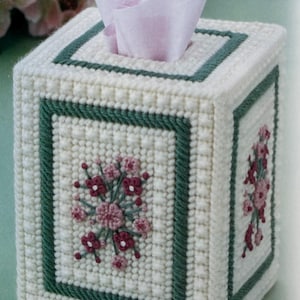 Puede incluir: Tapa de caja de pañuelos blanca con borde verde y bordado floral rosa.