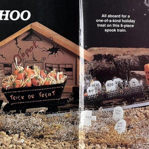 May include: A plastic canvas train set titled BOO! CHOO-CHOO featuring a black engine, a pumpkin car, a black coal car labelled TRICK OR TREAT, an orange tank car labelled WITCH'S BREW, and a grey passenger car, displayed with a wooden depot.
