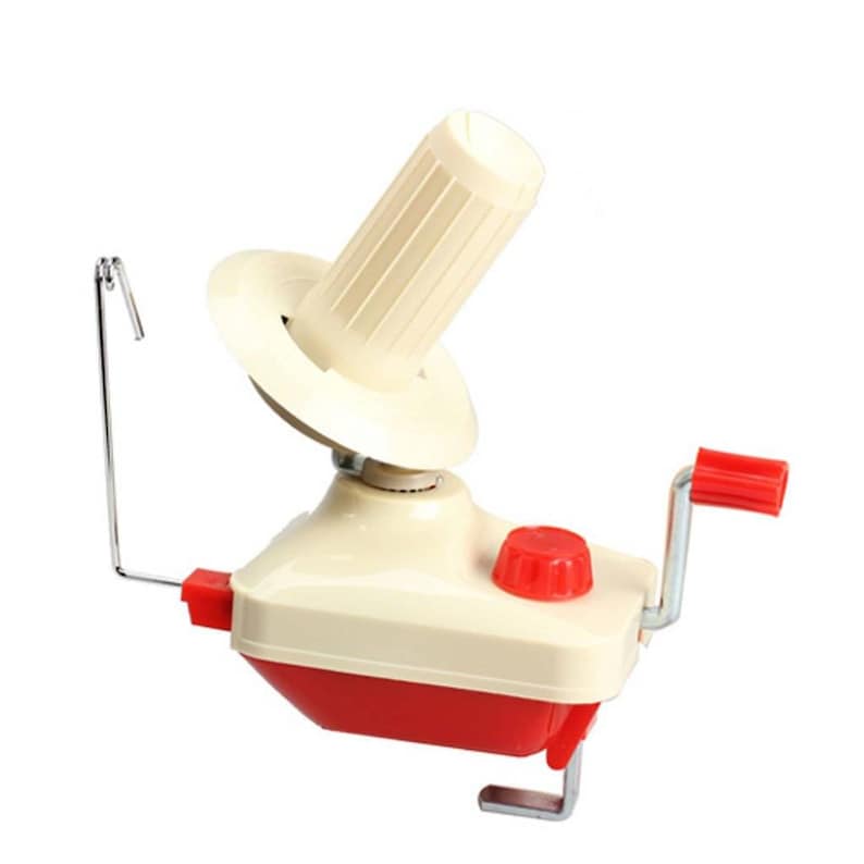May include: A cream and red yarn winder with a red handle and knob. The yarn winder has a cream-colored cone and a metal hook. The base is red and cream-colored, with a metal clamp for securing it to a table.