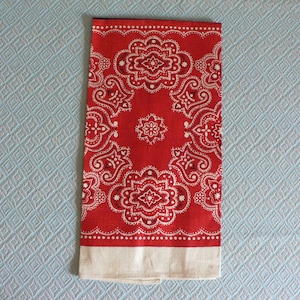 May include: Red bandana with a white paisley pattern. The bandana has a white border.