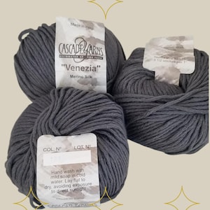 May include: Three skeins of dark gray "Venezia" Merino Silk yarn by Cascade Yarns. The label reads "Made in Peru" and includes care instructions for hand washing with mild soap in cold water.