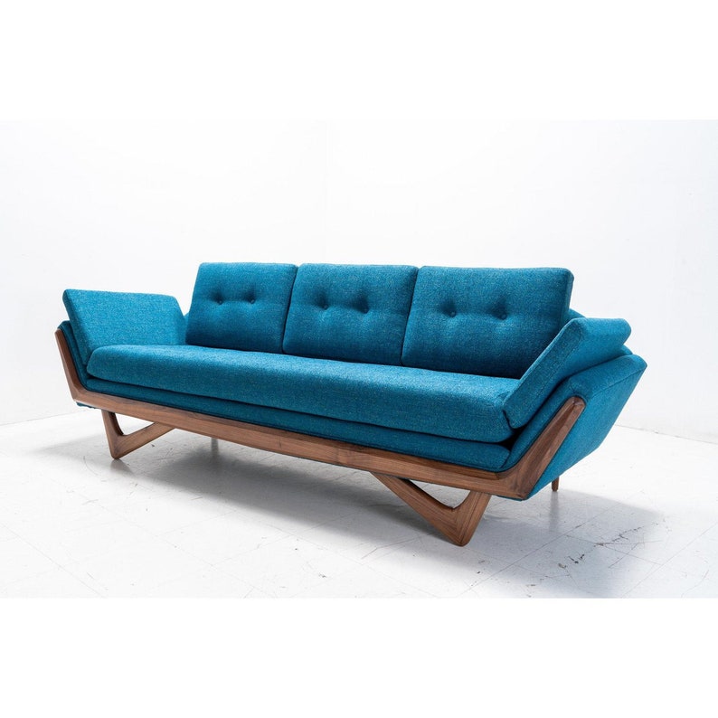May include: A teal blue mid-century modern sofa with a wood frame and angled legs. The sofa has three cushions and tufted upholstery.