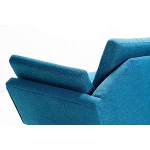 May include: A teal blue armchair with a high back and a single armrest. The chair is upholstered in a textured fabric.
