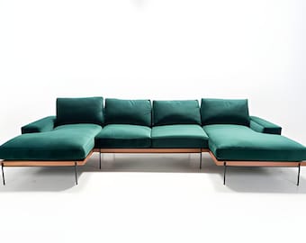 May include: A large, emerald green sectional sofa with a chaise lounge. The sofa has a wooden frame and black metal legs.