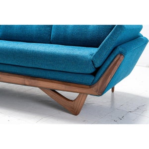 May include: A teal blue sofa with a wooden frame and angled legs. The sofa has a tufted back and a deep seat.