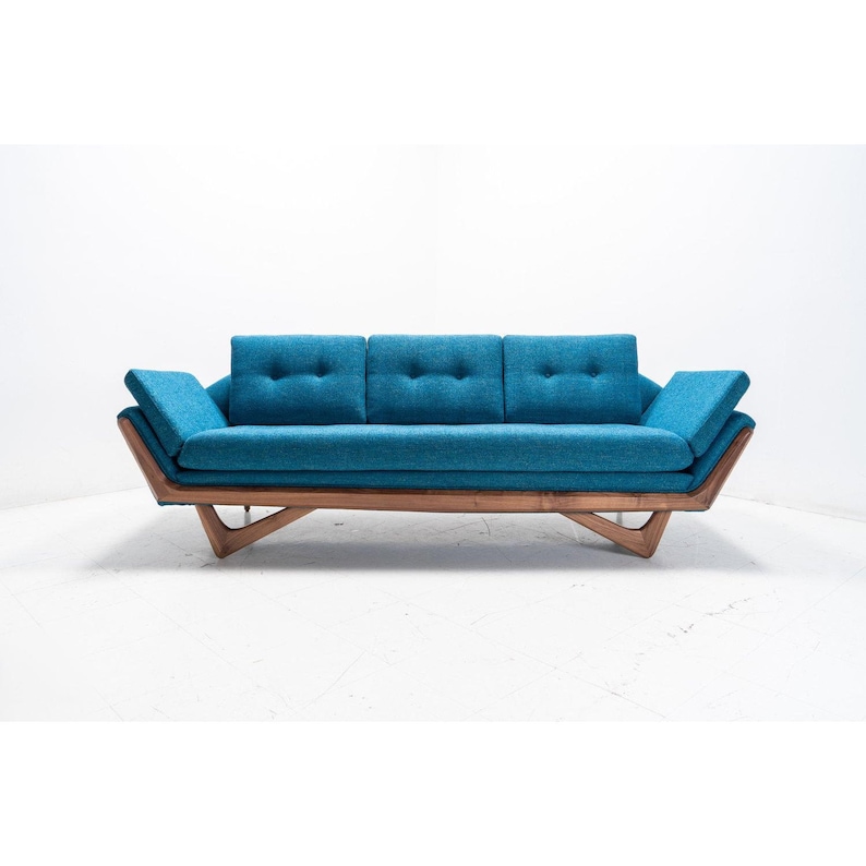 May include: A teal blue mid-century modern sofa with a wood frame and angled legs. The sofa has three cushions and is upholstered in a textured fabric.
