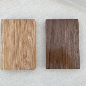 May include: Two wood samples, one light brown and one dark brown, showing the grain of the wood.