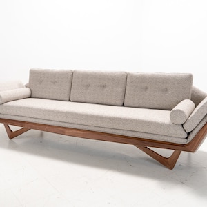 May include: A light gray fabric sofa with a wooden frame and angled legs. The sofa has three cushions and two throw pillows.