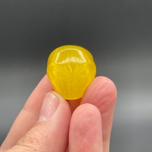 Può includere: Una caramella gommosa gialla a forma di testa aliena.