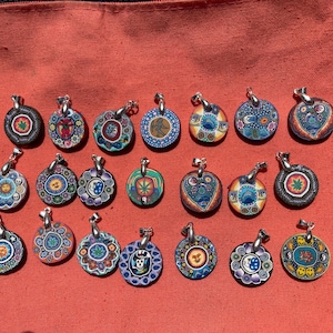 May include: A collection of 18 round pendants with colorful designs. The pendants are made of wood and have a silver metal bail. The designs include flowers, geometric patterns, and abstract art.