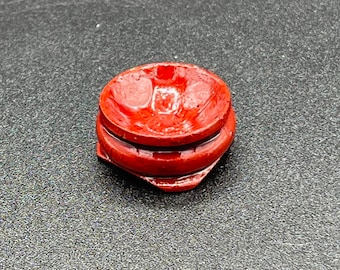 May include: A small, round, red wooden display stand for crystals or other small objects.