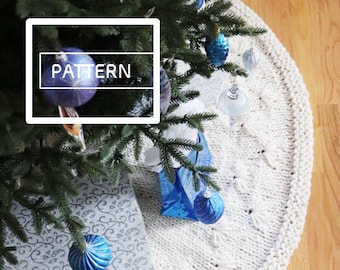 Könnte beinhalten: Ein weißer gestrickter Christbaumrock mit einem zarten Muster. Der Rock ist mit blauen und silbernen Ornamenten und einer verpackten Geschenkbox verziert.