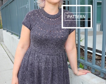 May include: A gray knitted dress with a lace pattern around the neckline and hem. The dress has short sleeves and a fitted bodice. The model is wearing the dress with a silver bracelet on her wrist.