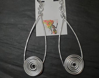 May include: Silver wire earrings with a spiral design. The earrings are long and dangle. The earrings are handmade and unique.