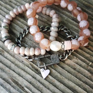 May include: Three bracelets with pink and white beads, a silver chain with a diamond clasp, and a small silver heart charm.