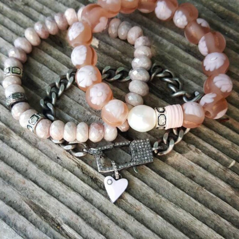 May include: Three bracelets with pink and white beads, a silver chain with a diamond clasp, and a small silver heart charm.
