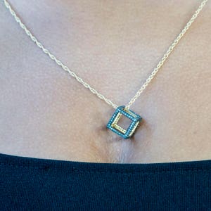 May include: A gold chain necklace with a black diamond cube pendant.