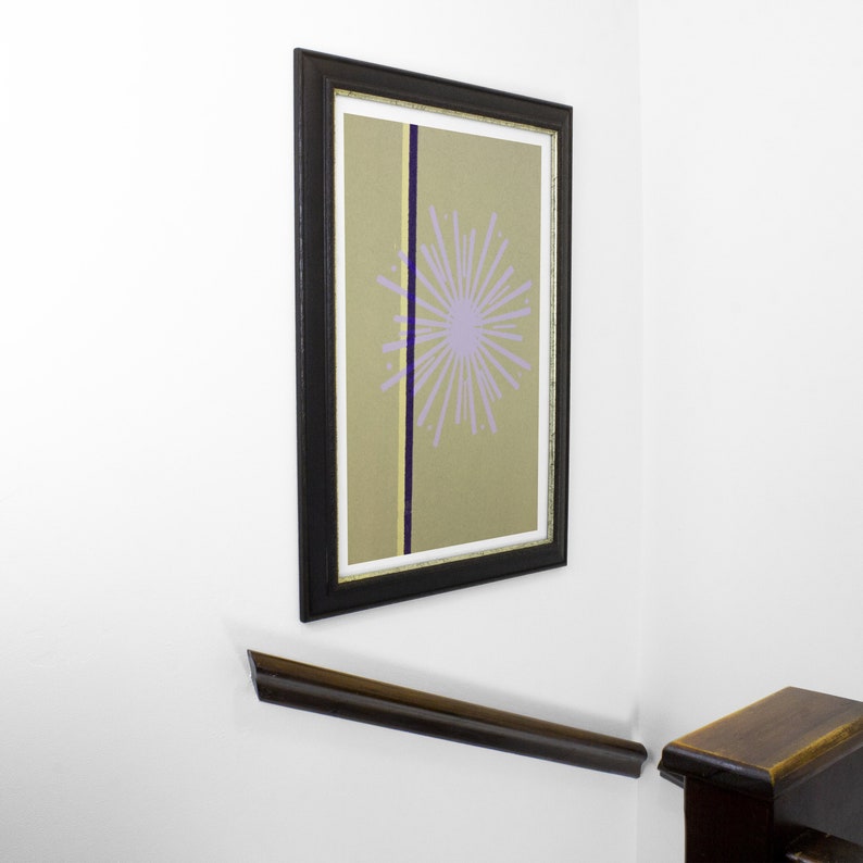 Op de afbeelding: Een ingelijste print met een zwarte lijst en een beige achtergrond. Een paarse bloem met een gele kern bevindt zich in het midden van de print. Een zwarte en gouden lijn loopt verticaal door het midden van de print.