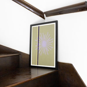 Op de afbeelding: Een ingelijste print met een geometrisch ontwerp in tinten paars, geel en bruin. Het ontwerp bevat een gestileerde stervorm op een lichtbruine achtergrond.