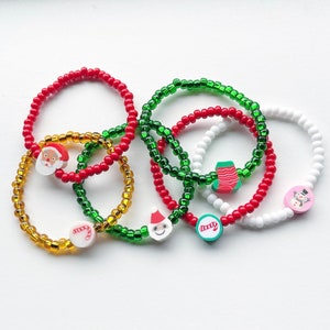 Puede incluir: Conjunto de seis pulseras con tem&aacute;tica navide&ntilde;a con cuentas rojas, verdes y blancas. Las pulseras tienen dijes de Santa Claus, un mu&ntilde;eco de nieve, un bast&oacute;n de caramelo, una media y un &aacute;rbol de Navidad.