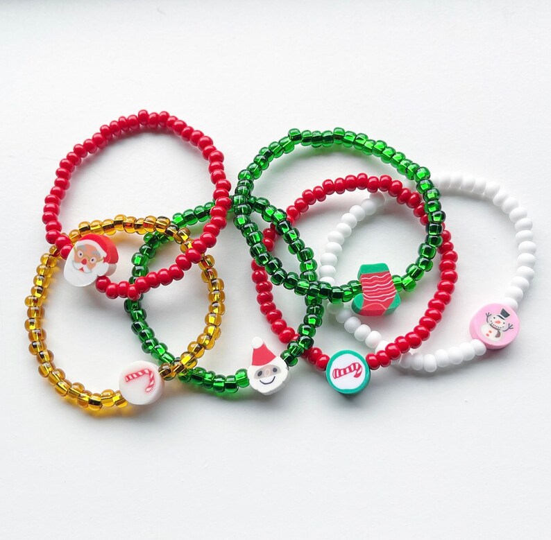 Puede incluir: Conjunto de seis pulseras con tem&aacute;tica navide&ntilde;a con cuentas rojas, verdes y blancas. Las pulseras tienen dijes de Santa Claus, un mu&ntilde;eco de nieve, un bast&oacute;n de caramelo, una media y un &aacute;rbol de Navidad.