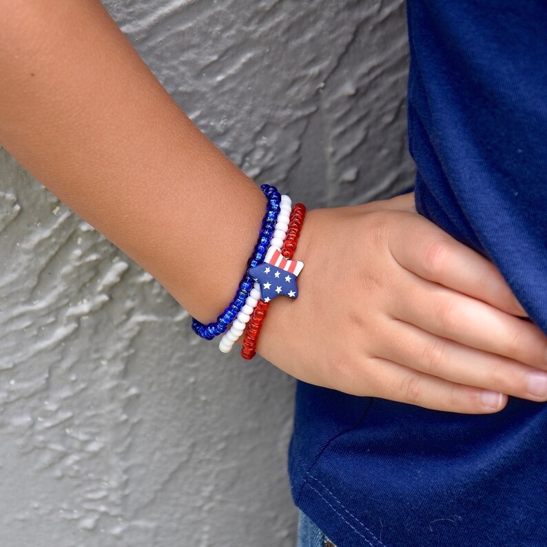 May include: A red, white, and blue beaded bracelet with a star-shaped charm featuring an American flag design.