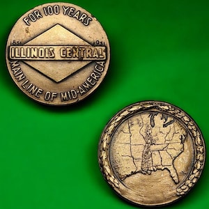 May include: Two bronze commemorative coins. One coin reads "FOR 100 YEARS" and "ILLINOIS CENTRAL MAIN LINE OF MID-AMERICA" with dates 1851-1951. The other coin features a map of the central United States.