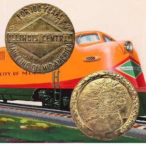 May include: Two gold-colored commemorative coins with text and a map of the United States. The coins are in front of an orange and red Illinois Central train. One coin reads "FOR 100 YEARS" and "ILLINOIS CENTRAL".