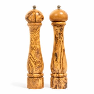 May include: Two tall pepper mills crafted from light brown wood with a distinct swirling grain pattern. Each mill features a rounded top, a slender hourglass-shaped body, and a small metallic knob at the very peak for adjusting the grinding mechanism.