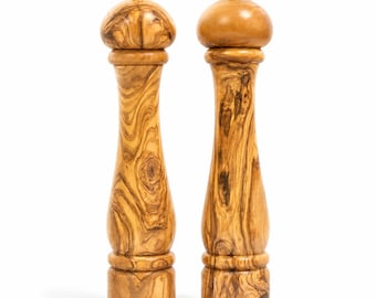 May include: Two tall pepper mills crafted from light brown wood with a distinct swirling grain pattern. Each mill features a rounded top, a slender hourglass-shaped body, and a small metallic knob at the very peak for adjusting the grinding mechanism.